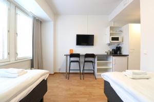 赫尔辛基Forenom Aparthotel Helsinki Herttoniemi公寓式酒店的带两张床的房间和带桌子的厨房