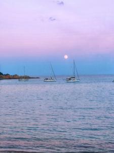 阿尔巴塔克斯porto frailis Arbatax casa vista mare的日落时分三艘船坐在水中