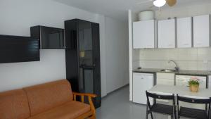 萨洛Apartamentos Amatista的厨房配有沙发、桌子和冰箱。