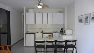 萨洛Apartamentos Amatista的厨房配有白色橱柜和桌椅