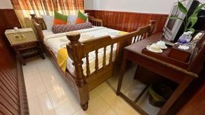 暹粒欧卡1别墅酒店的一间卧室配有一张木床和一张桌子及一台电视