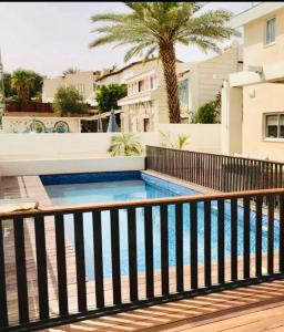 埃拉特Glamour Luxury Suite Swimming pool的一个带围栏和棕榈树的游泳池