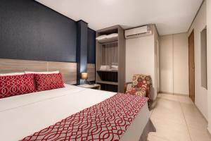 帕尔马斯103 Hotel & Flats的一间卧室配有一张带红色枕头的床和一把椅子