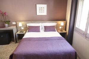 坎布里尔斯Hostal Fonda Montserrat的一间卧室配有一张大床,提供紫色床单和枕头