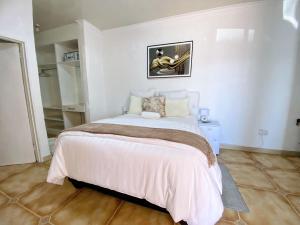 帕拉佩Ranzi Court Guest House的一间白色客房内配有一张大床的卧室