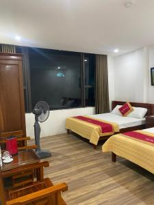 格卢市社Khách sạn An Phú Cửa Lò的酒店客房带两张床、一张桌子和一盏灯