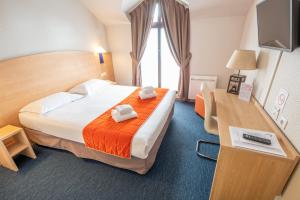 塞纳河畔诺让圣罗兰酒店的酒店客房设有一张大床和一张书桌。