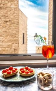 焦维纳佐Dimora nel Palazzo Ducale的桌上的两份比萨饼,配上一杯饮料,还有一扇窗户
