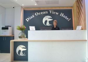 莫塞尔湾Diaz Ocean View Hotel的站在鱼海景酒店柜台后面的女人
