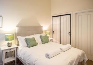 BallogieThe Kennels的卧室配有带绿色枕头的大型白色床