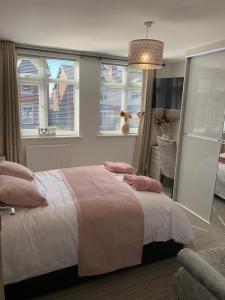 乔利Kensington Luxury Apartment on Gated Development in Leafy edge of Chorley Town Centre的一间卧室配有带粉红色枕头的床和窗户。