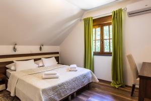 普利特维采湖金湖酒店的一间卧室配有一张带绿色窗帘的床和窗户。