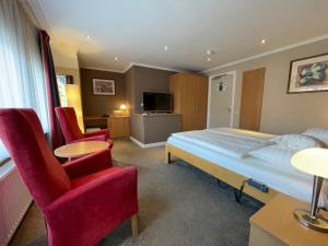 黑耶拉特阿尔贝茨兰德酒店的一间卧室配有一张床、两把椅子和电视