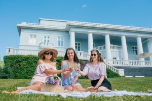 波尔沃海科庄园及水疗中心酒店的三个女人坐在一条毯子上,在白色房子前面