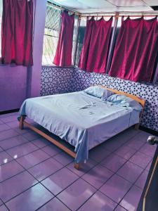 普卡尔帕Casa sanacion Elixir的紫色地板和窗户的客房内的一张床位