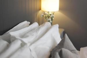 PotterspuryThe Old Talbot Hotel Milton Keynes的一张带白色床单的床和花瓶