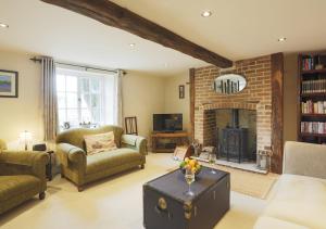 米尔登霍尔Walnut Tree Cottage的客厅设有壁炉、沙发和椅子