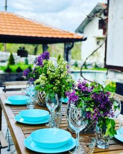 BoljevacONOMAD的一张带蓝色盘子、玻璃杯和紫色花卉的木桌