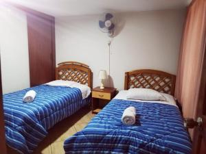 利马Hostal Turístico El Cajamarquez的一间卧室配有两张带毛巾的床