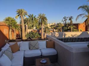 马拉喀什Riad Rossi的天井配有沙发、棕榈树和桌子