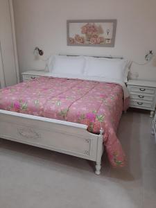 维泰博La casetta nella Tuscia的一张带粉红色棉被的床和两张床头柜