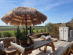 诺德韦克Cabin De Duinweg: direct aan duin en bos的甲板上配有带草伞的木桌