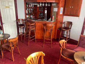 斯凯格内斯Ivydene Guest House的酒吧配有木椅和带葡萄酒瓶的吧台