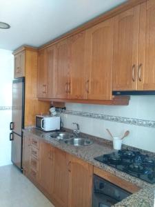 萨各夫雷纳MARIANS的厨房配有木制橱柜、水槽和冰箱。