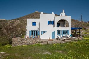 纳乌萨Kolimpithres beach house的山上的白色房子,设有蓝色的门和椅子