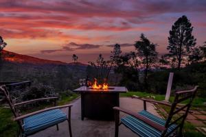 North ForkSierra Vista Lookout Lodge with Creek, Waterfall and Waterholes, minutes from Bass Lake and Yosemite South Gate的露台上的火坑,配有两把椅子,享有日落美景