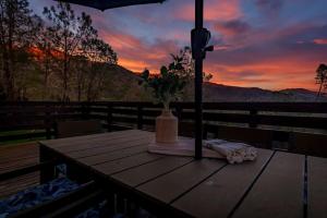 North ForkSierra Vista Lookout Lodge with Creek, Waterfall and Waterholes, minutes from Bass Lake and Yosemite South Gate的木桌,甲板上有一花瓶
