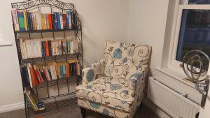 斯陶尔波特Waters Edge, Town house in Stourport-on-Severn的书架旁的椅子,书架上摆放着