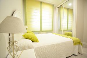 桑亨霍Apartamento en pleno centro de Portonovo, Sanxenxo的白色卧室配有床和灯