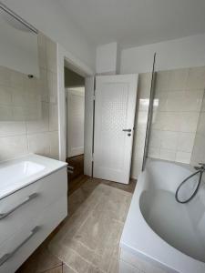 利希滕费尔斯Korbstadt-Villa Rattan-Design mit Balkon, Garten, Arbeitsplatz, Küche的白色的浴室设有浴缸和水槽。