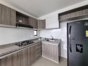 佛罗里达布兰卡Apto Botero 1308 - WAIWA HOST的厨房配有黑色冰箱和木制橱柜。