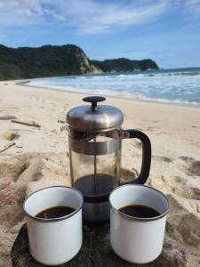 TandulujanggaCamp Tarimbang的咖啡壶和沙滩上的2杯