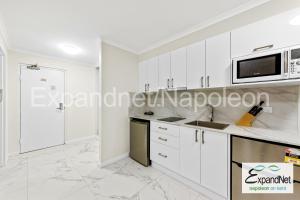 悉尼拿破仑肯特酒店的厨房配有白色橱柜和微波炉