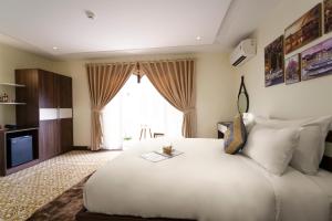 会安Hawal Boutique Villa Hoi An的卧室配有一张白色大床和电视。