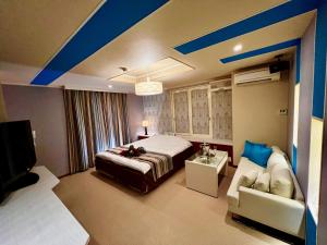 驹根市ホテル南の風風力3駒ヶ根店的一间卧室配有一张床、一张沙发和一台电视。