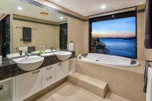 汉密尔顿岛埃奇公寓酒店的一间带两个盥洗盆和浴缸的浴室以及大窗户。