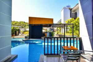 奥南海滩Aonang Viva Resort - SHA Plus的阳台的游泳池配有两把椅子和一张桌子