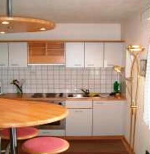 切尔梅斯佩西恩安杰古特酒店的厨房配有白色橱柜和一张带粉红色凳子的桌子