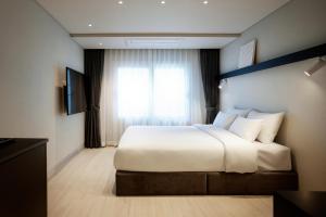 首尔The Connoisseur Residence Hotel的卧室设有一张白色大床和一扇窗户。