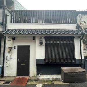 大阪茶隐の宿的白色的房子,设有黑色的门和阳台