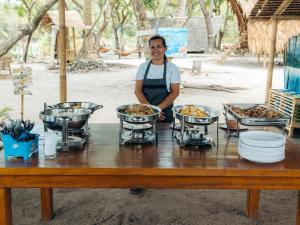 爱妮岛Isla - The Island Experience的站在木桌前,吃着食物的人