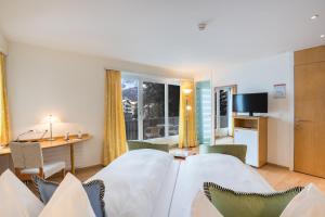 马洛亚施瓦泽豪斯瑞士优质酒店的配有一张床、一张书桌和一扇窗户的酒店客房