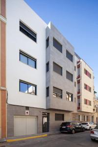 塞维利亚Stunning apartment in Nervion with parking的一座高大的白色建筑,汽车停在停车场