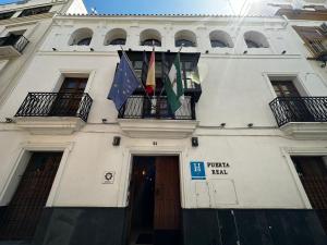 塞维利亚Boutique Puerta Real的悬挂着国旗的白色建筑,从阳台上悬挂
