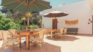 伊斯费古耶拉尔海滩Hostal Esfigueral的一个带桌椅和遮阳伞的庭院