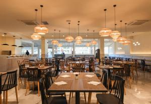 科林比亚Delfinia Resort - All Inclusive的餐厅设有木桌、椅子和吊灯。